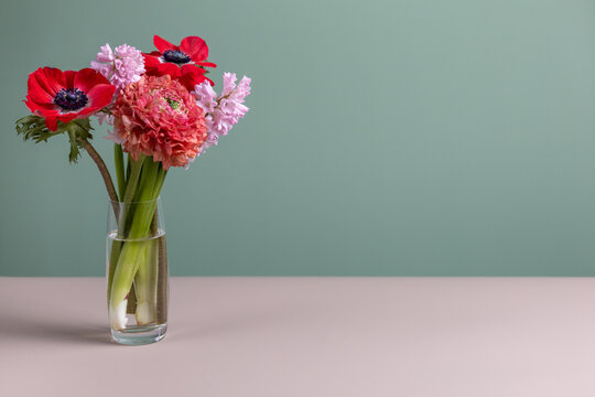 Bright background with bouquet of beautiful flowers of hyacinths, anemones and ranunculus in glass vase. Front view, copy space. Valentine’s Day, Women’s Day, Mother’s Day, birthday, anniversary.