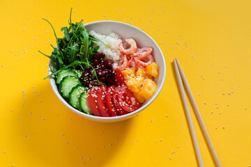Hawaiian poke bowl with seafood and fresh vegetables. Plate with shrimps, rice, tomato, cucumber,...