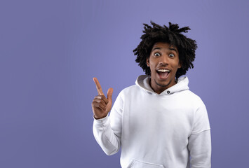 African American teen guy experiencing AHA moment, having creative idea, pointing up on violet background, copy space