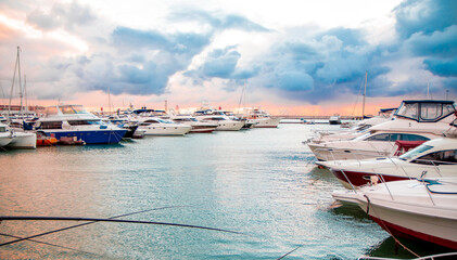 Yachts and boats are moored at the seaport at sunset. Marine parking for modern motor boats and...