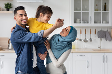 Portrait Of Cheerful Middle-Eastern Family Of Three Haaving Fun In Kitchen Together