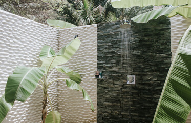 Amazing outdoor shower with banana trees growing inside in a resort hotel bungalow on an exotic...