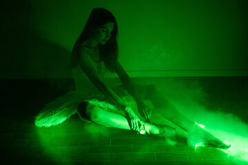 Ballerina with long legs posing in green light