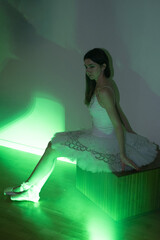 Ballerina with long legs posing in green light