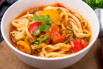 Lagman asian soup with meat, vegetables and noodles, dark table, uzbek cuisine