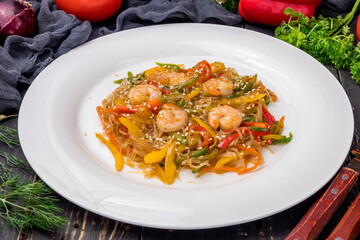 fried Rice noodles with shrimp and vegetables funchosa on dark table