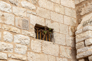 Side window with metal grill on the outer wall of the Church of Nativity in Bethlehem in the...