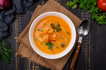Tom Yam soup with shrimps on white bowl on dark table top view