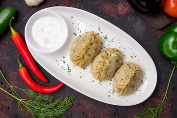 Manty with beef on white plate with sour cream, uzbek cuisine top view