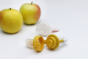 Nibblers with fresh apples on white table, closeup. Baby feeder.