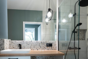 Stylish bathroom with ceramic bathroom sink on wooden counter, mirror on the wall and modern...