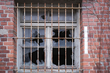 Vergittertes Fenster mit zerschlagenen Scheiben