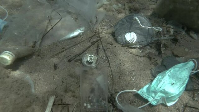 Dead Greater weever fish (Trachinus draco) hitting trapped in plastic bag lies inside plastic bag on the seabed among the medical face mask, plastic and other garbage. Plastic pollution of Ocean.  
