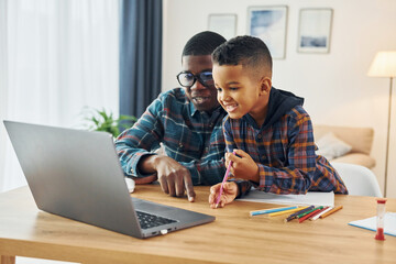 Fototapeta na wymiar With laptop on table. African american father with his young son at home