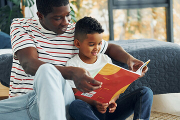 In domestic room. African american father with his young son at home