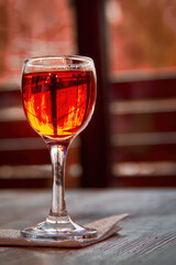 Glass of cognac on wooden table. Shot glass on the background of a window.