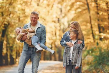 Four people. Happy family is in the park at autumn time together