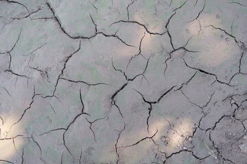 Sun beams on dry cracked gray ground, shadow close-up