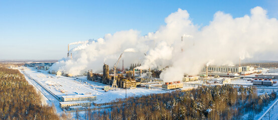 Industrial landscape. Panoramic view of the technological pipe and industrial infrastructure. Chemical production with red-white pipes and smoke is coming. Production buildings.
