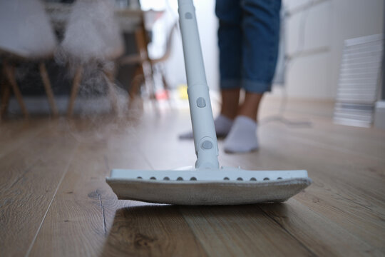 A steam mop washes the parquet on the floor of the house