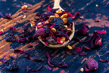 wooden spoon with dried flower berry tea on an old wooden background close up