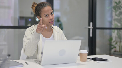 African Woman Pointing at Camera while using Laptop in Office