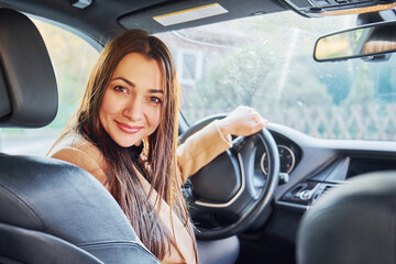 Vehicle interior. Woman is sitting in modern black colored automobile