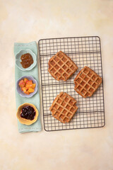 Top view of vegan, gluten free waffles with jam and fruit toppings ready to eat. Healthy, tasty homemade breakfast or dessert.