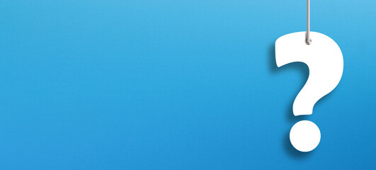 White question marks suspended by ropes with copy space on blue background