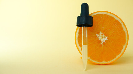 Pipette with citrus essence with half an orange on a light background. The concept of natural skin care products and cosmetics. Oranges, halved with peel, orange oil
