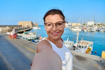 Woman taking photo against the backdrop of historic fortress, sea bay