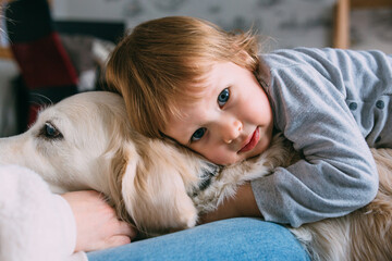 Cute baby and his labrador retriever at home on the bed.