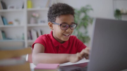Cheerful schoolboy doing online hometask, typing on laptop at home, education - Powered by Adobe