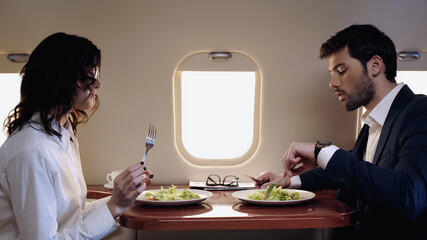 Business people sitting near fresh salads in private jet.