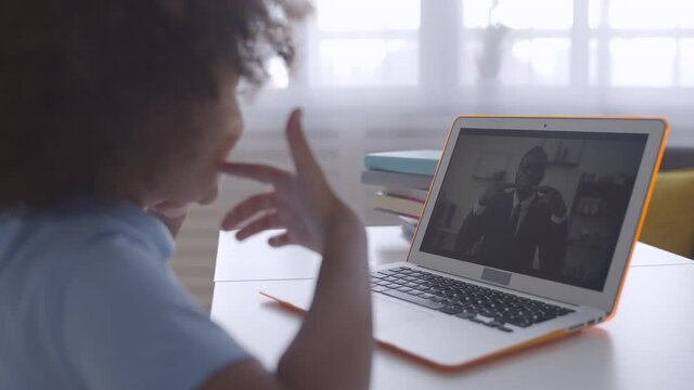 Pupil learning foreign language with online tutor, sitting in front of laptop