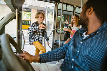 Black driver smiling while talking with multiracial pupils