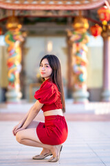 Portrait beautiful smiles Asian young woman wearing red cheongsam dress traditional decoration for Chinese new year festival celebrate culture of china at Chinese shrine Public places in Thailand