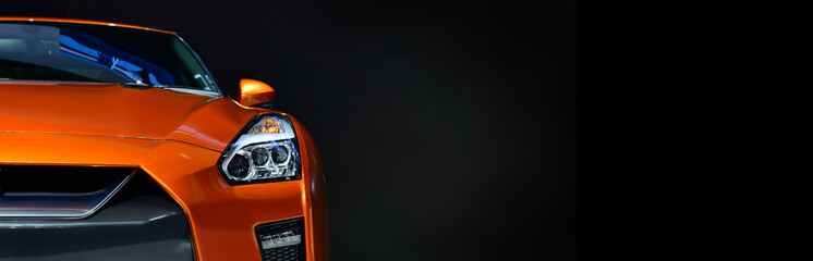 Orange modern car headlights on black background, copy space, banner side