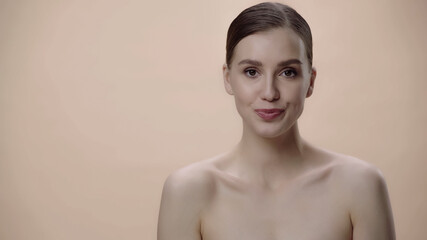 young woman with clean face and bare shoulders isolated on beige.