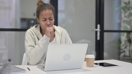 African Woman Coughing while using Laptop in Office