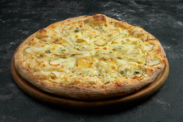 Pizza with pear, dor blue cheese on a black stone background. 45 degree angle view. Close-up, selective focus