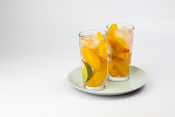 Summer drink. Peach juice or tea with peach slice and mint on white background.