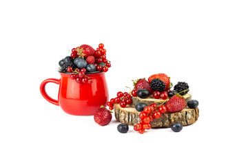 Ripe berries mixed assortment in red cup and wooden board or podium with berry on white background. Summer or Spring Organic Berry background.