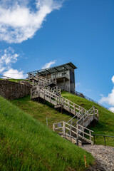  landscape view with observation tower in the blue sky, wooden stairs and spring green gras
