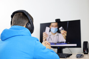 Online consultation with a doctor, man listens to the physician recommendations sitting in front of the PC webcam. Person in headphones during video chat or watching TV program about health