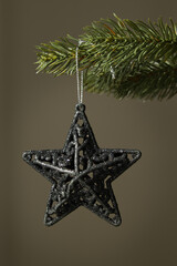 Close-up of a black Christmas tree star decoration on a dark background. New year concept. Dark moody photography style with selective focus and copy space
