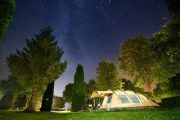 A camping tent surrounded by green trees under the starry sky in luxembourg - Powered by Adobe