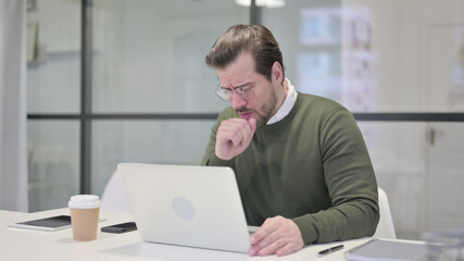 Young Businessman Coughing while using Laptop in Office