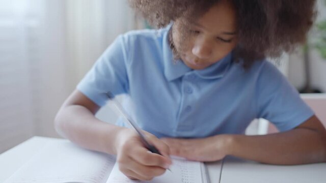 Little girl studying at home, writing down math problems, homeschooling