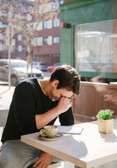 young man in a grey jacket writing and laughing something in note book while taking a coffee at the bar. Writing down his fresh ideas. High quality photo